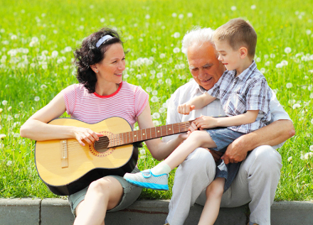 A therapist playing music with a child and grandfather. Click to learn more about the group and individual services we can provide your loved one.